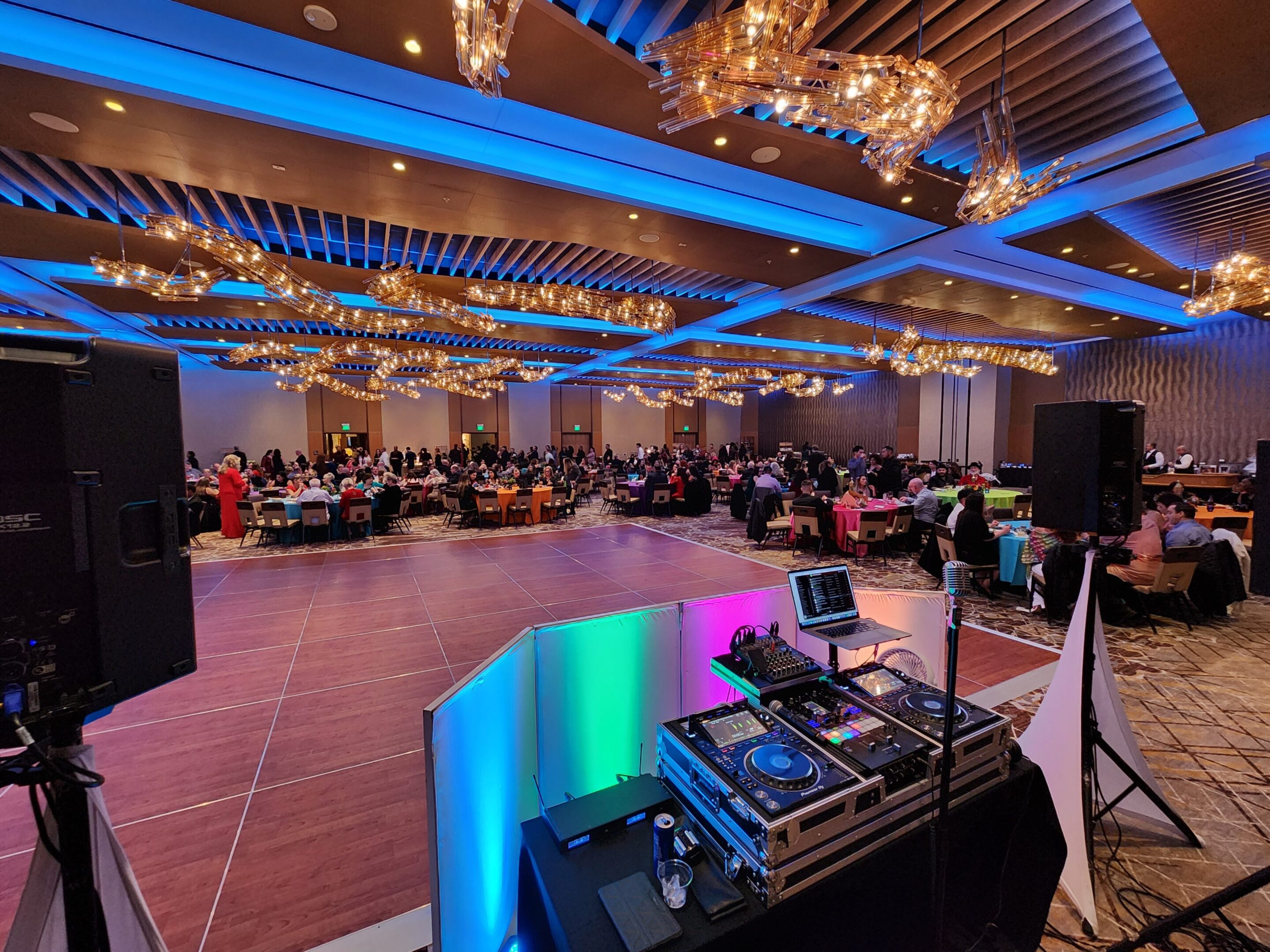 A festive banquet hall with string lights and chandeliers, set for a large event.