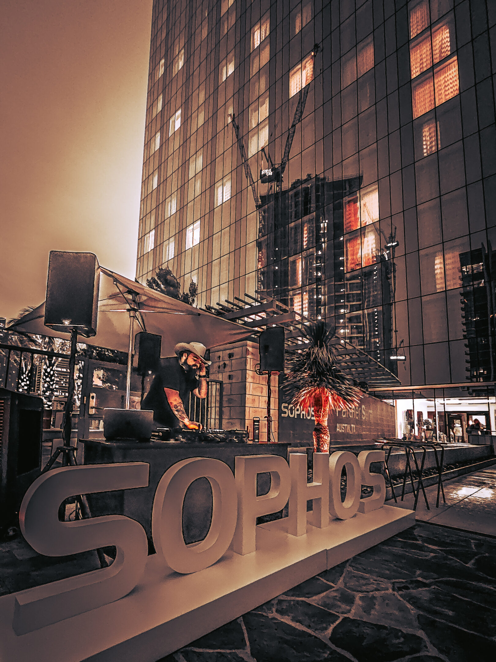 Evening city scene with illuminated SOPHOS sign in front of a building.