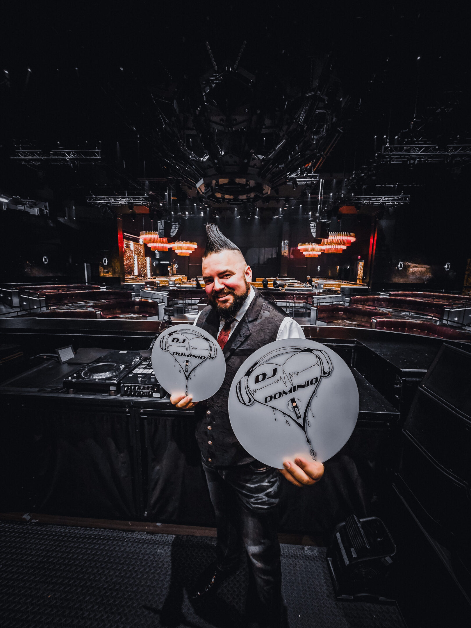 Man holding two drum heads with signatures in a concert venue.