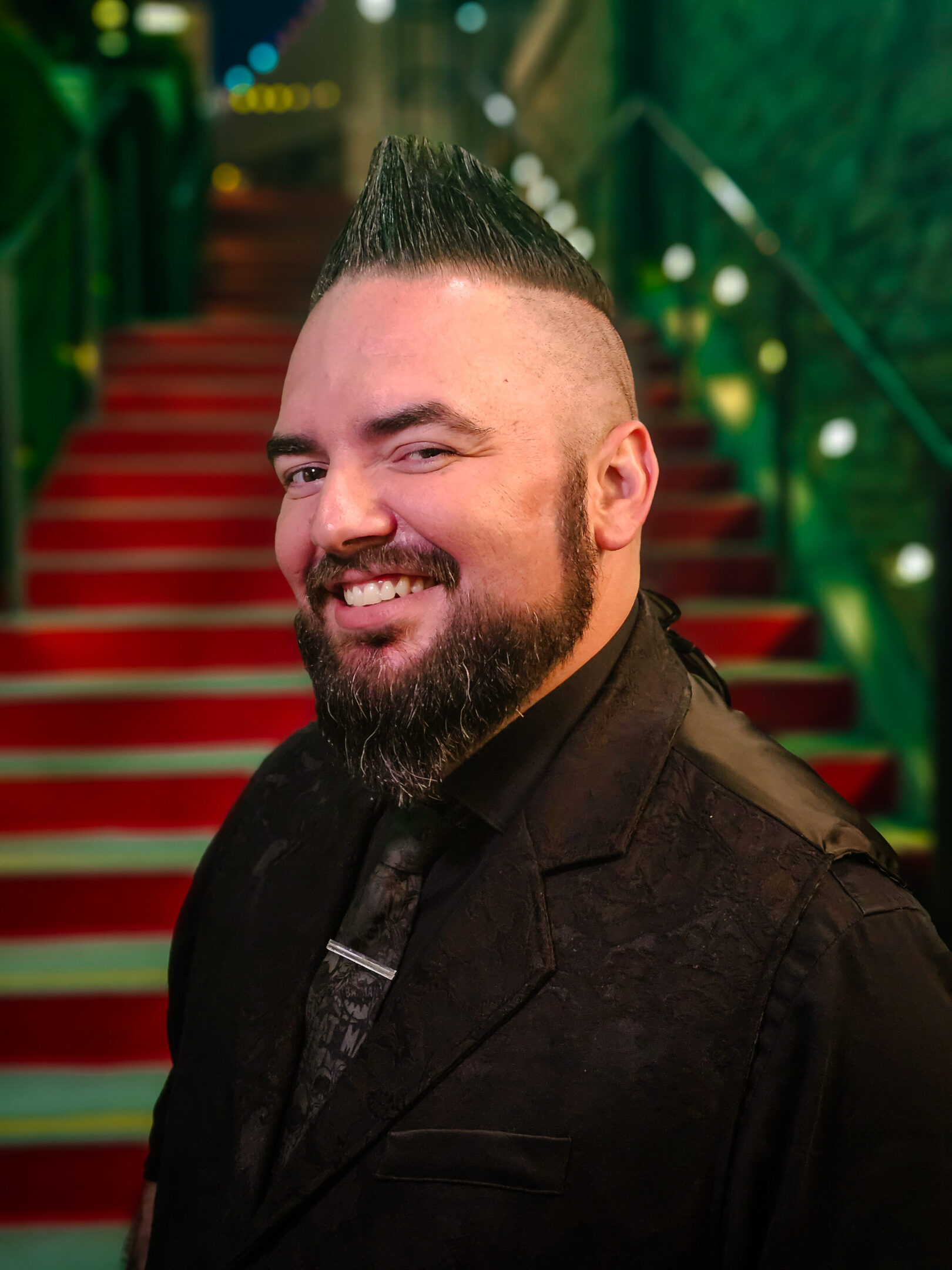 Smiling man with a mohawk hairstyle in formal attire.