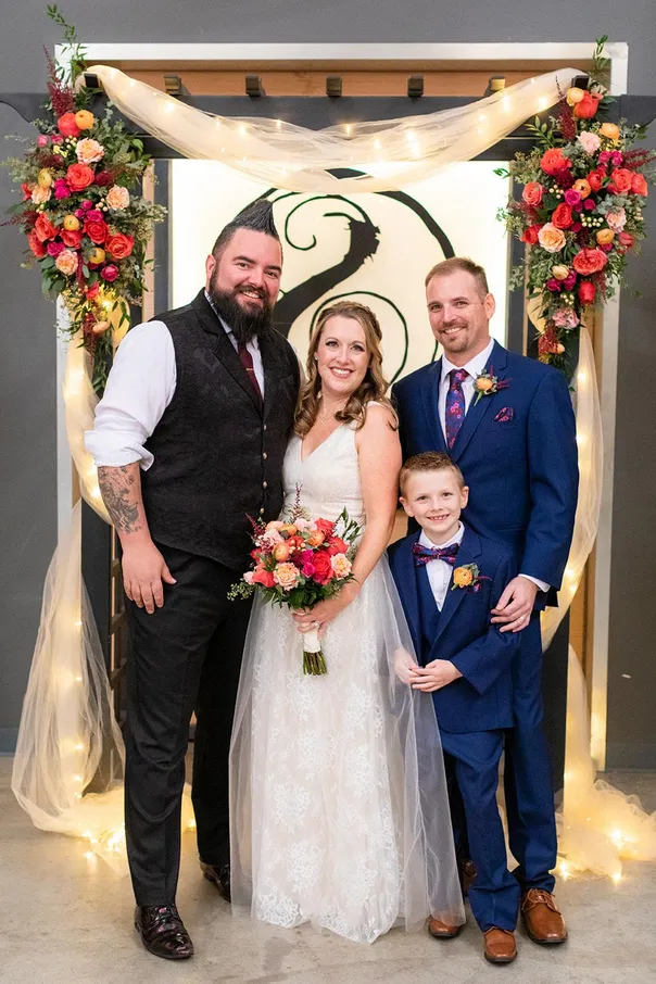 A bride and groom with two guests at a wedding ceremony.