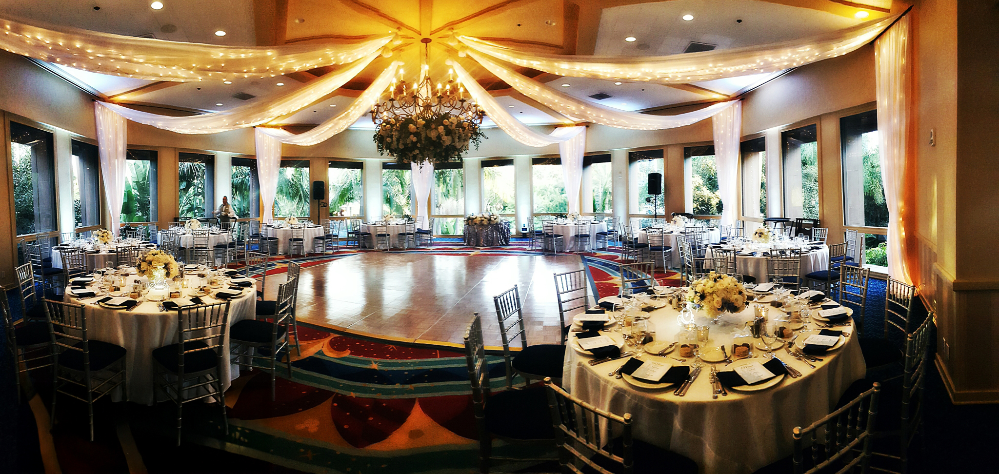 Elegant banquet hall with round tables and decorative ceiling drapes.